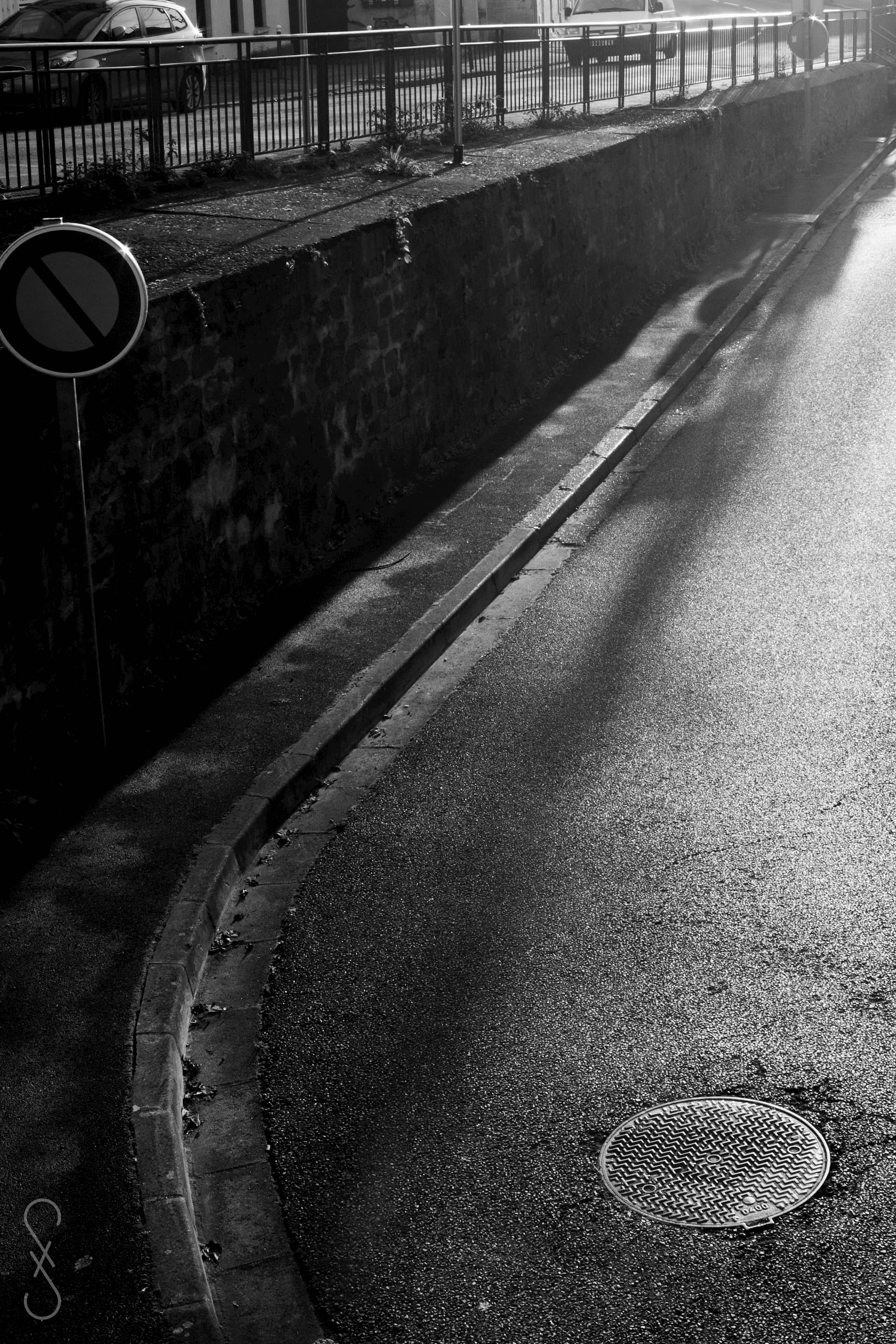 Une rue vide, le bord d'un trottoir, se courbe et s'enfuit vers le coin droit de l'image.